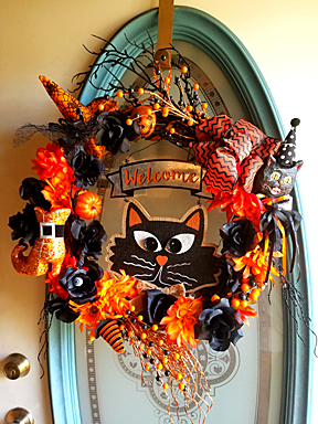 Front door wreath featuring a cartoon Halloween cat.