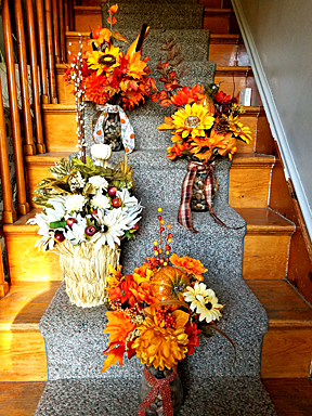 Four baskets of silk flowers shown on a staircase.