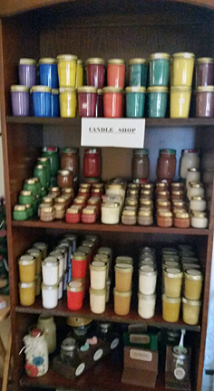 This is a "candle shop" display on a vertical shelving cabinet. There are many jars with colorful waxes shown.