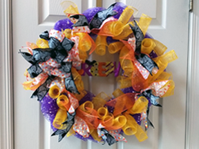Wreath with Halloween theme, sing purple and gold netted ribbons in curly-Qs and swirls, with added blue ribbons, etc.