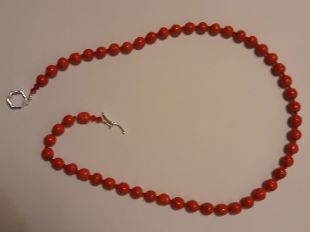 A string of blood-red round beads for a ladies necklace, approximately 18 inches. Clasp is the toggle through circle kind.