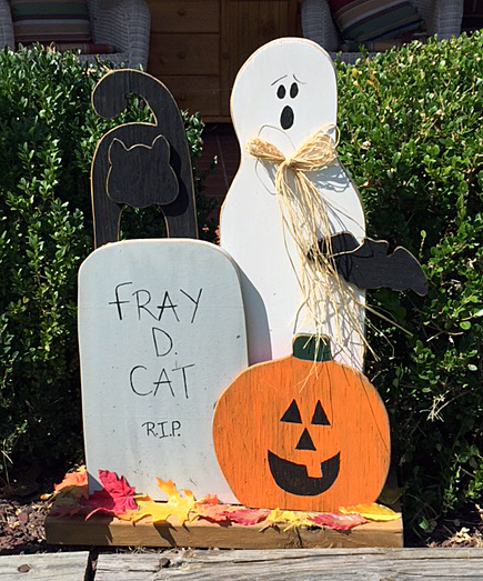 ghost, pumpkin, black cat, and tomb reading Fray D. Cat