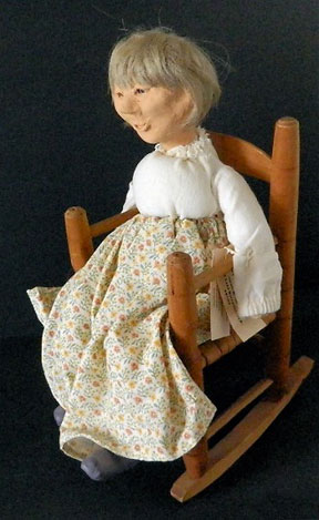 A hand-made cloth doll of an old woman in a rocking chair.