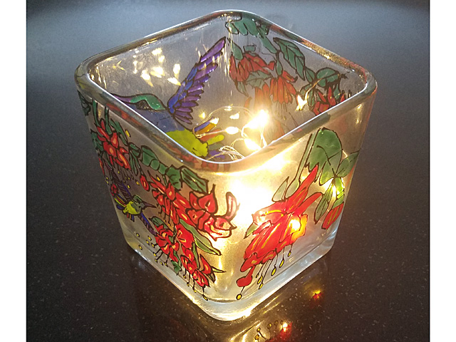 A tea-light holder has been decorated with greenery such as poinsettias and mistletoe.