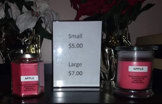 A sign says "Small $5.00 Large $7.00". On the left is an octagonal jar and on the right is a round jar that's a bit bigger.  Both are labeled "Apple" and have a fuschia pink color.