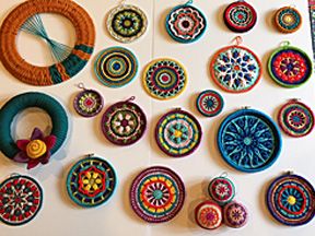 Crocheted and woven wall art using hand-spun yarn into round designs.